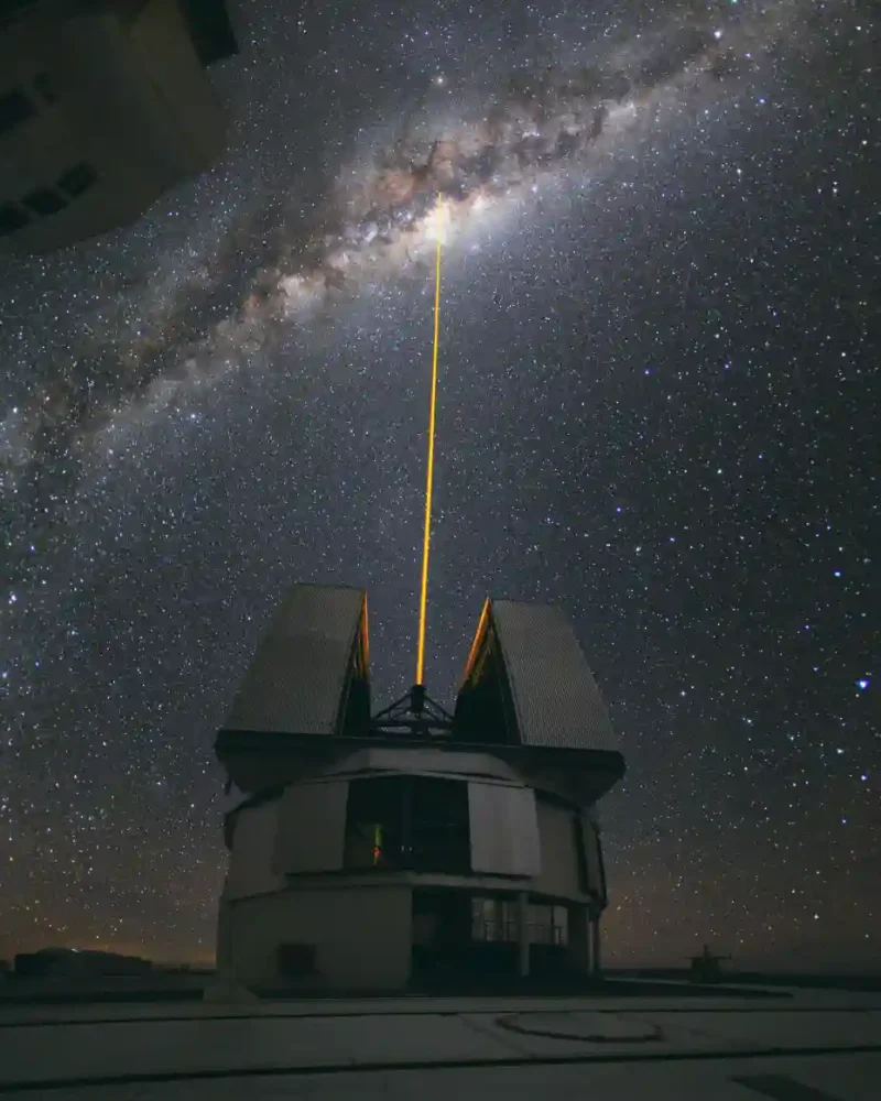 A green laser beam aimed toward the center of the Milky Way above an observatory