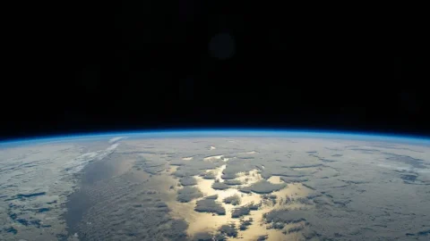Earth’s thin blue atmosphere glowing along the horizon against black space