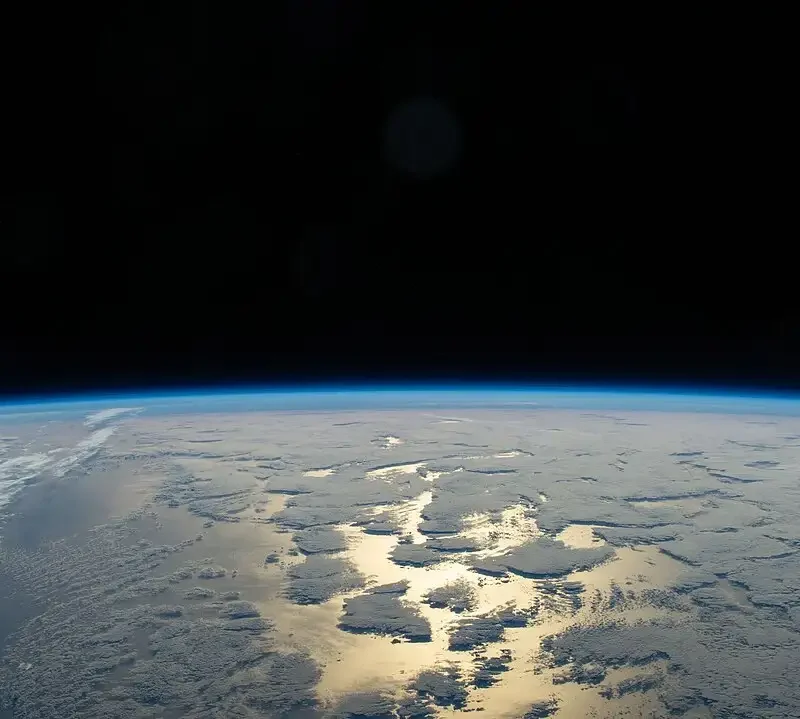 Earth’s thin blue atmosphere glowing along the horizon against black space