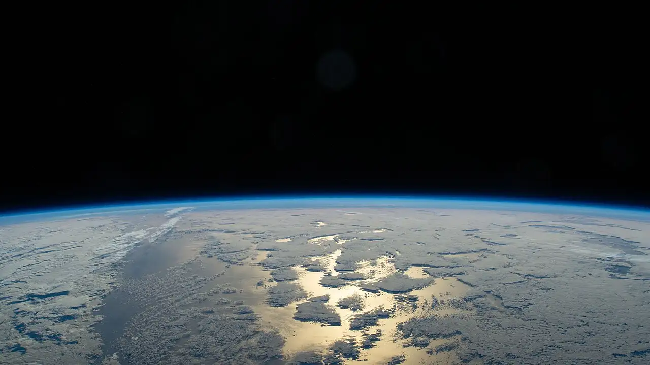 Earth’s thin blue atmosphere glowing along the horizon against black space