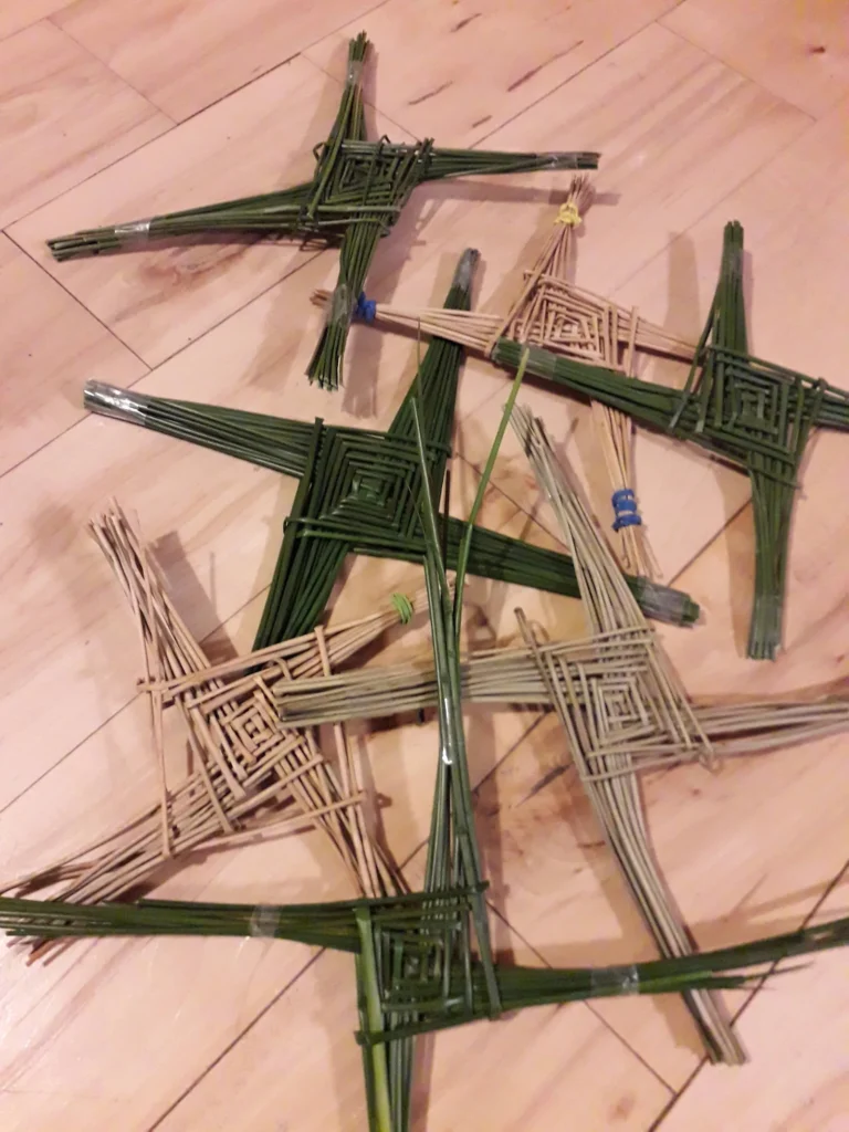 Green and dried rush crosses laid together on a wooden surface