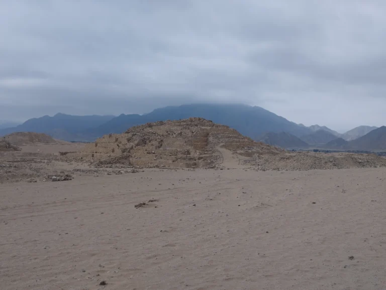 Ancient stepped platform at Caral beneath a cloudy sky