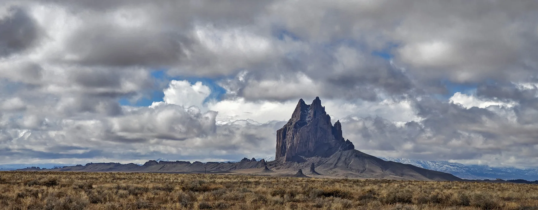 Shiprock’s jagged volcanic peak and exposed rock walls beneath clouds in New Mexico.