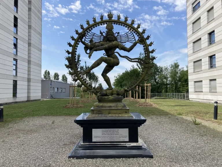 Shiva Nataraja statue inside a ring of flames between buildings at CERN